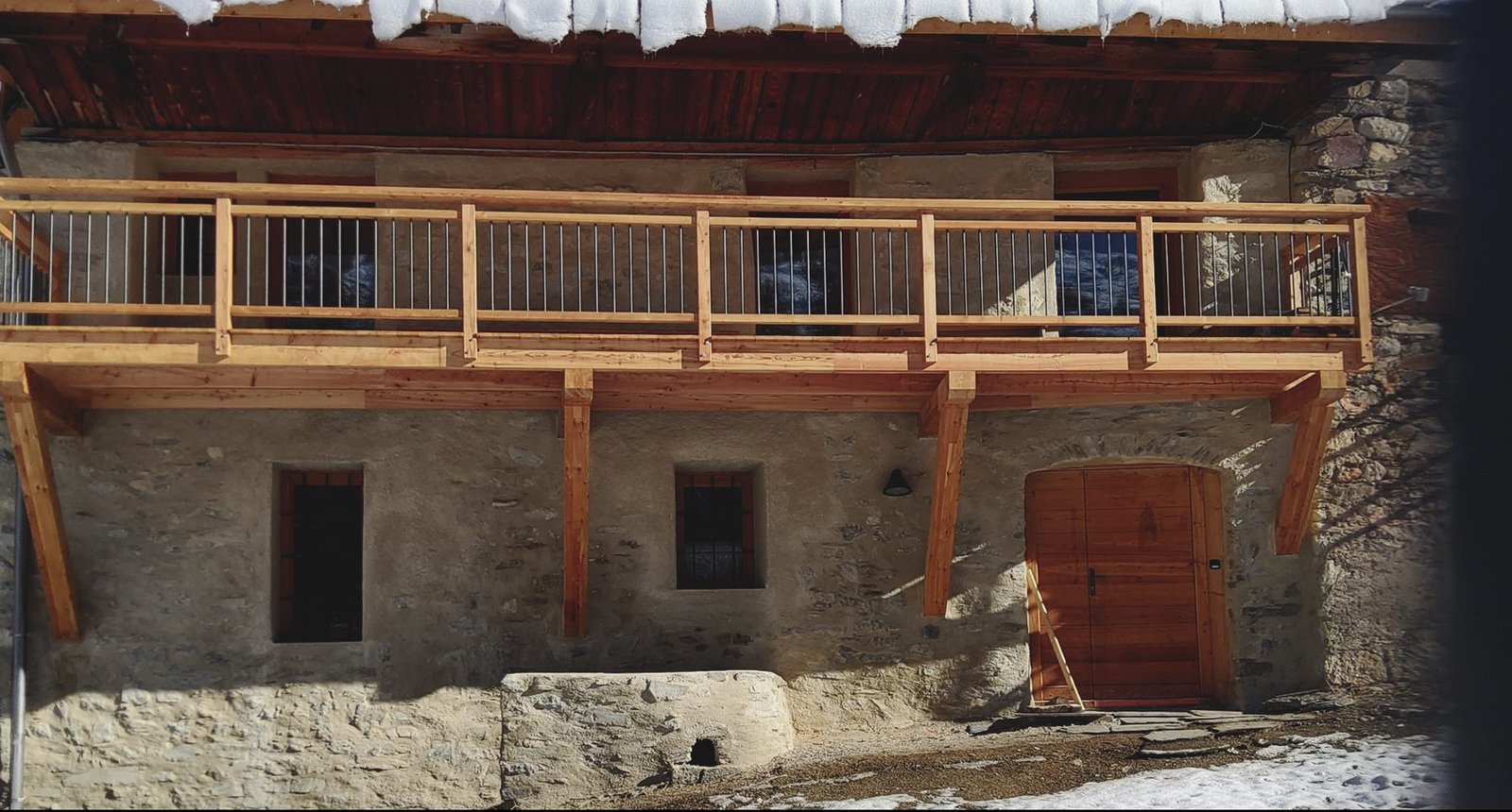 Balcon en bois sur façade en pierre